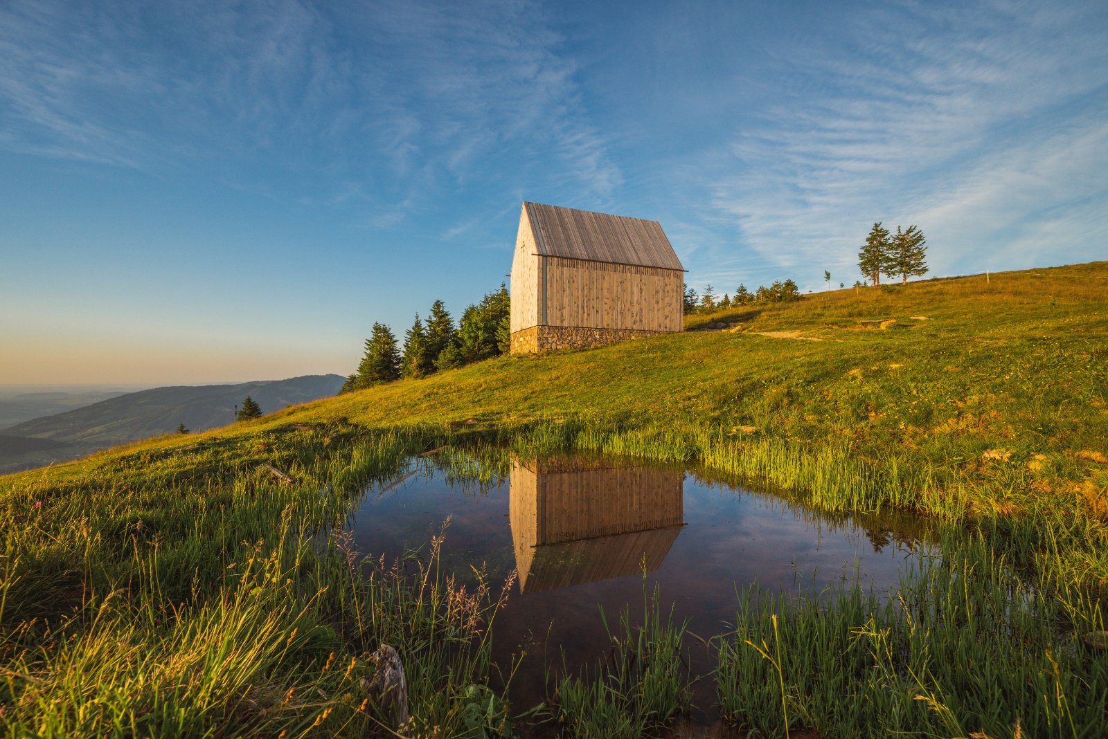 Eine kleine Kapelle am Hang, ihr Spiegelbild hält das Wasser fest. Auch das gehört zum Golfherbst: die Passstrassen und Ausflüge dazwischen.