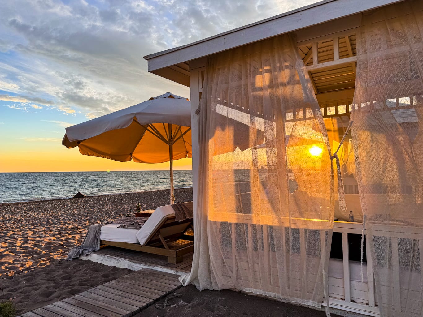 Am privaten Strand, zwischen sanft wehenden Vorhängen der Daybeds, klingt der Golf-Feierabend im Kempinski