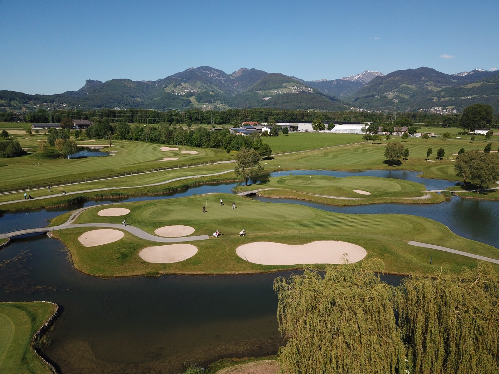Das Tal atmet, die Berge rahmen ein. Wo Golfer und Familien das Grün teilen, endet jede Frage nach Sinn.